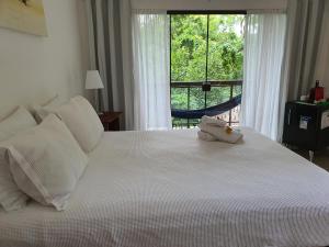 a bedroom with a large white bed with a window at Ohana suíte Abraão - Ilha Grande in Abraão