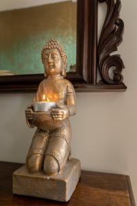 une statue d'un buddha tenant une bougie dans l'établissement B&B De Buren, à Gasselte