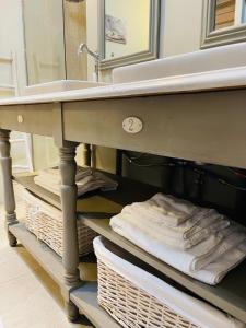 - un lavabo dans la salle de bains avec des serviettes sur une étagère sous un lavabo dans l'établissement La Bastide des Songes - Demeure d'hôtes, à Robion