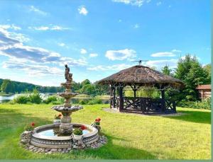 een fontein in een tuin met een prieel bij Hotelik Wulpink Majdy Olsztyn in Majdy