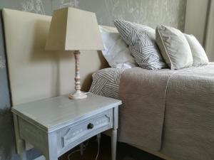 a lamp on a table next to a bed with pillows at Chambres La Belle Vue in Dinant