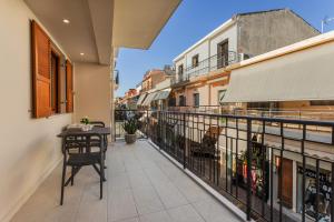 einen Balkon mit einem Tisch und einem Zaun in der Unterkunft Gallery Art Apartment Chania Crete in Chania