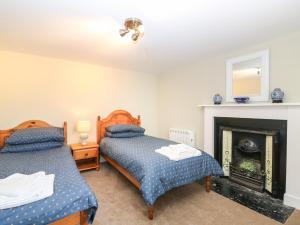 zwei Betten in einem Zimmer mit Kamin in der Unterkunft Garden Cottage in Elgin
