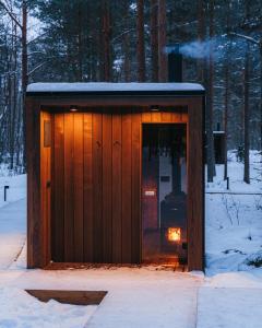 a wooden shed with a light in the snow at ÖÖD Hötels Laheranna SUME -with sauna in Punakivi