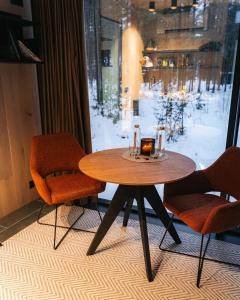 a table with a candle and two chairs and a window at ÖÖD Hötels Laheranna SUME -with sauna in Punakivi