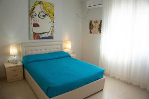 a bedroom with a blue bed and a painting on the wall at Duplex Apartment Front Sea in Vlorë