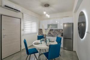 a dining room with a white table and blue chairs at Emerald Luxury Apartments in Nikiti