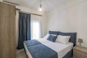 a bedroom with a blue and white bed and a window at Emerald Luxury Apartments in Nikiti