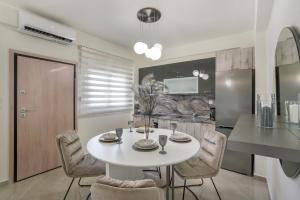a kitchen and dining room with a white table and chairs at Emerald Luxury Apartments in Nikiti