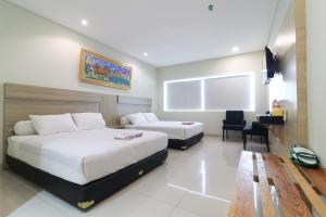 a hotel room with two beds and a desk at Locus Rooms in Bandung
