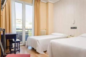 a hotel room with two beds and a window at Hotel Madrid Río in Madrid