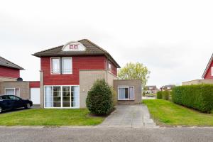 a red house with a car parked in front of it at Maxime 292 - Kustpark Village Scaldia in Hoofdplaat