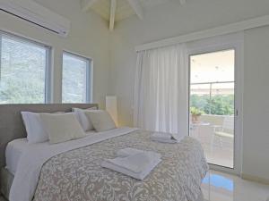 a white bedroom with a large bed with towels on it at Sunray studio in Poros in Poros
