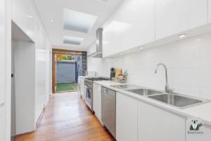 a white kitchen with a sink and a counter at KOZYGURU Redfern Lovely 2 Bedroom Terrace 1x FREE Parking NRE005 in Sydney