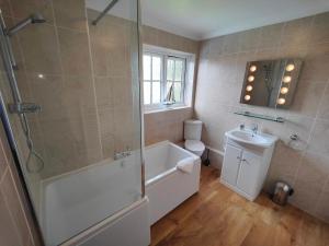 een badkamer met een bad, een wastafel en een douche bij Birdsong Rural Winchester Twyford - 2BR, 5BR, 7BR - sleeps upto 16 in Winchester