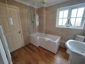 een badkamer met een bad, een wastafel en een raam bij Birdsong Rural Winchester Twyford - 2BR, 5BR, 7BR - sleeps upto 16 in Winchester