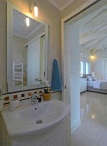 a white bathroom with a sink and a bedroom at Sunray studio in Poros in Poros