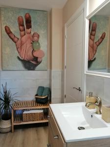 a bathroom with a sink and a hand painting on the wall at El estudio del Duero in Tordesillas