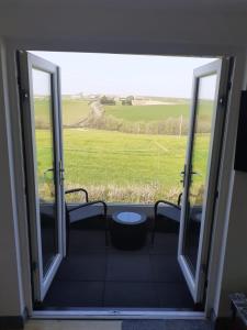 Une porte ouverte s'ouvre sur un balcon offrant une vue sur un champ. dans l'établissement The Coach House Annexe, à Barnstaple