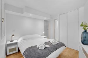 a white bedroom with a bed with towels on it at LE CONSTANTIN - Charmant souplex de 34m2 in Toulouse