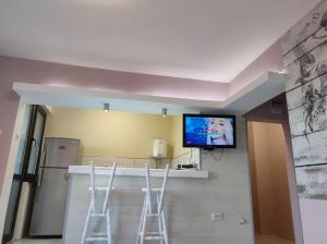 a kitchen with two bar stools and a tv on the wall at Апартамент Съншайн in Burgas