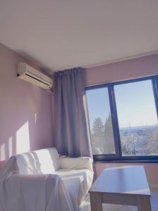 a room with a bed and a table and a window at Апартамент Съншайн in Burgas