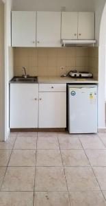 達西亞的住宿－MIRABELLO HOTEL APARTMENTS，厨房配有白色橱柜、水槽和冰箱。