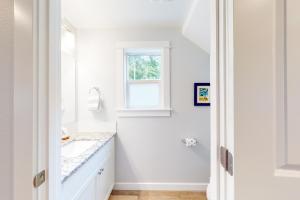 a white bathroom with a sink and a window at The Shore Pine in Manzanita +23 photos