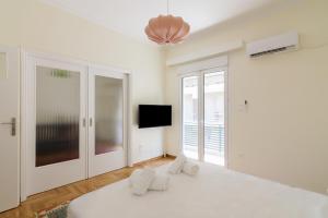 um quarto branco com uma cama e uma televisão em Bright and Spacious 2-bedrooms Apartment in Athens em Atenas