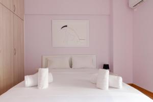um quarto branco com uma cama branca com almofadas brancas em Bright and Spacious 2-bedrooms Apartment in Athens em Atenas
