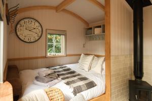 a bedroom with a bed with a clock on the wall at Piano Forte - delightful rural shepherd hut retreat & hot tub available in Rushford