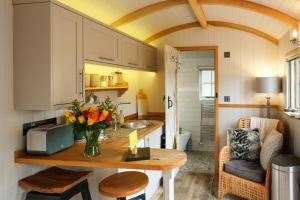 a kitchen with a table with a vase of flowers at Piano Forte - delightful rural shepherd hut retreat & hot tub available in Rushford