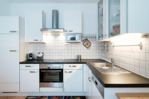 - une cuisine blanche avec évier et four micro-ondes dans l'établissement Casa Cigno by Quokka 360 - relaxation and sunshine assured, à Minusio