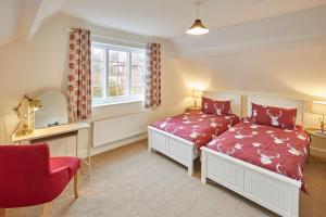 1 dormitorio con 2 camas y silla roja en Host & Stay - Gardeners Cottage, en Brafferton
