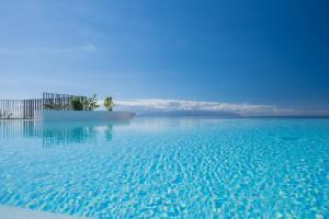 a swimming pool with blue water and a view of the ocean at Los Jardines de Abama Suites in Guía de Isora