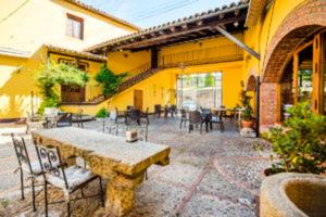 un patio con tavolo e sedie in un edificio giallo di La Hostería de Oropesa a Oropesa