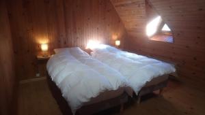 a large bed in a wooden room with two lights at Fermette typique auvergnate dans son écrin d'eau et de verdure in Saint-Donat