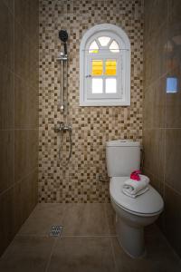 La salle de bains est pourvue de toilettes, d'une fenêtre et d'une douche. dans l'établissement Porto Giardino Apartments, à Kypseli
