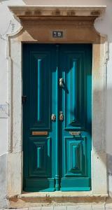 a green door on a building with the number at A Casa do Tenente in Faro