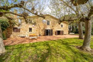 a stone house with a patio in the yard at Masia Marco Lux, ideal familias con gran zona exterior y Piscina in Llagostera