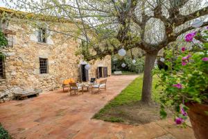 un patio avec une table et des chaises et un bâtiment en pierre dans l'établissement Masia Marco Lux, ideal familias con gran zona exterior y Piscina, à Llagostera