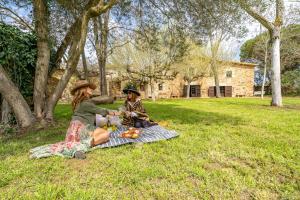 Deux femmes assises sur une couverture de pique-nique dans l'herbe dans l'établissement Masia Marco Lux, ideal familias con gran zona exterior y Piscina, à Llagostera