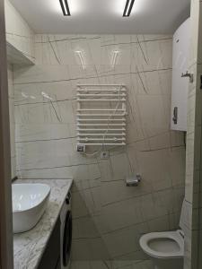 a white bathroom with a sink and a toilet at Orbi beach tower in Batumi