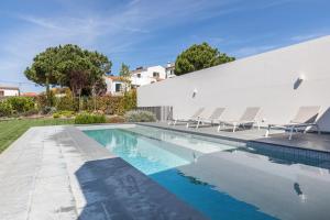 a swimming pool with chairs and a house at Casa de Cima Luxury Villa in Sintra