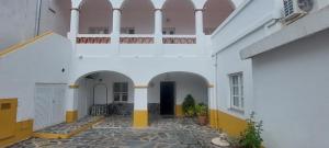 a white building with arches and a balcony at Guesthouse da Vila in Mourão
