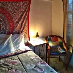 een slaapkamer met een bed, een stoel en een tafel bij Hospedagem Namastê in Visconde De Maua