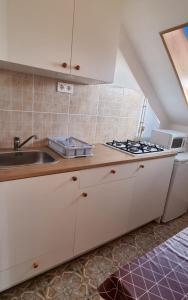 a kitchen with white cabinets and a sink at Boglári Harmónia Apartman in Balatonboglár