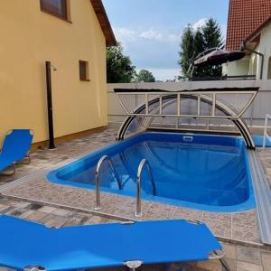 a blue swimming pool next to a house at Boglári Harmónia Apartman in Balatonboglár