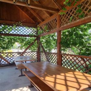 a wooden table and bench in a pavilion with trees at Boglári Harmónia Apartman in Balatonboglár