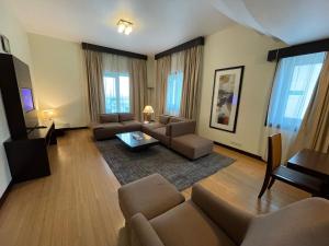 een woonkamer met een bank en een tafel bij Tulip Creek Hotel Apartments in Dubai